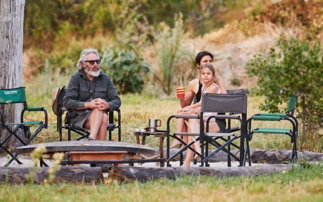Guests having coffee around the fireplace at Lazy River before going on a mokoro trip.